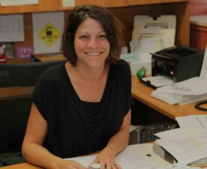 A female staff member sitting at her desk and smiling